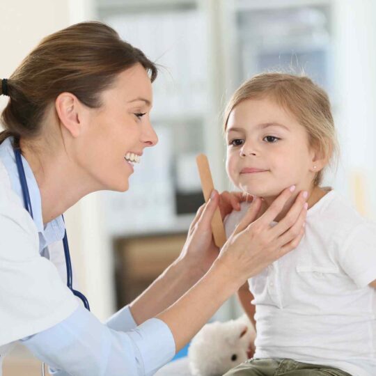 child with a doctor holding a tongue depressor