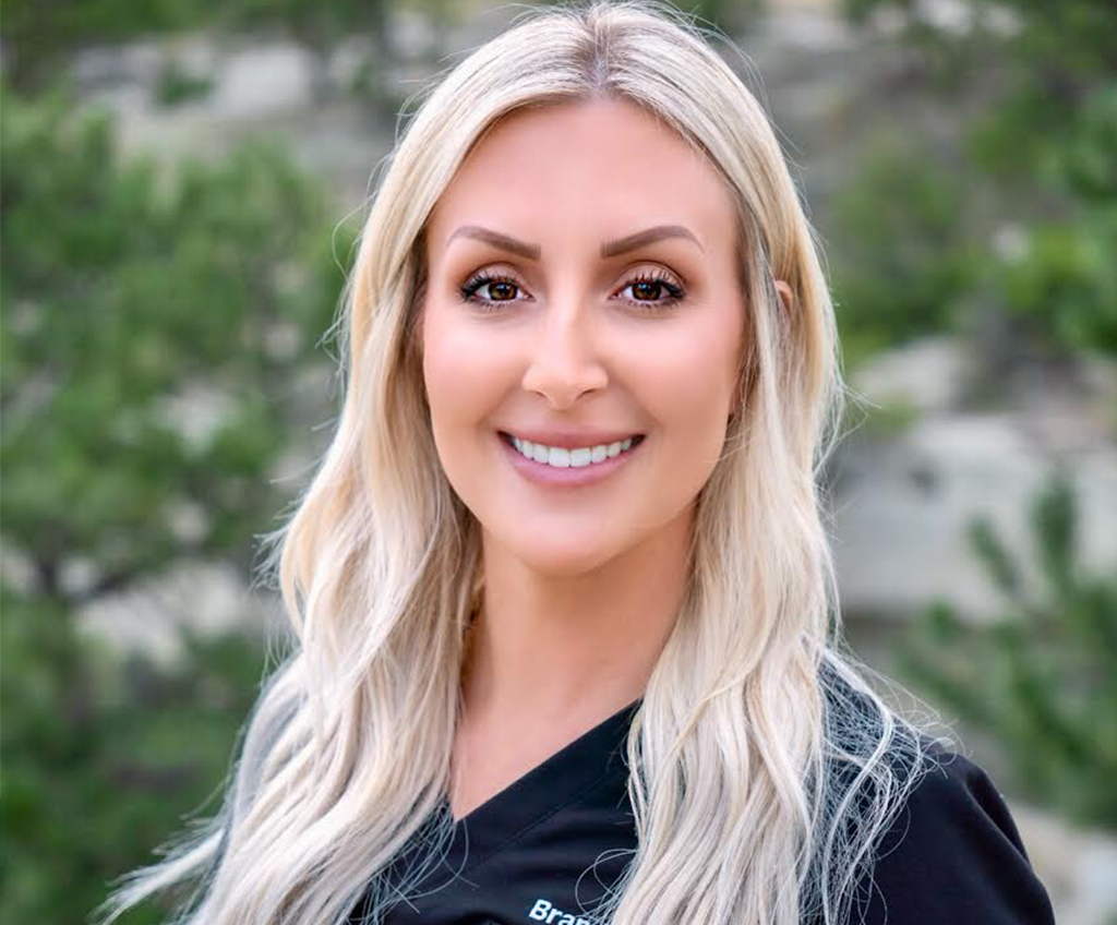 A woman Brandy with blond hairs and smiling with blurry background